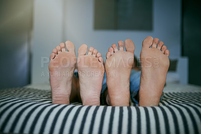 Buy stock photo Closeup shot of a young couple lying barefoot in bed