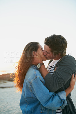 Buy stock photo Shot of an affectionate young couple bonding at the beach