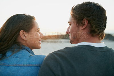 Buy stock photo Rearview shot of an affectionate young couple bonding at the beach