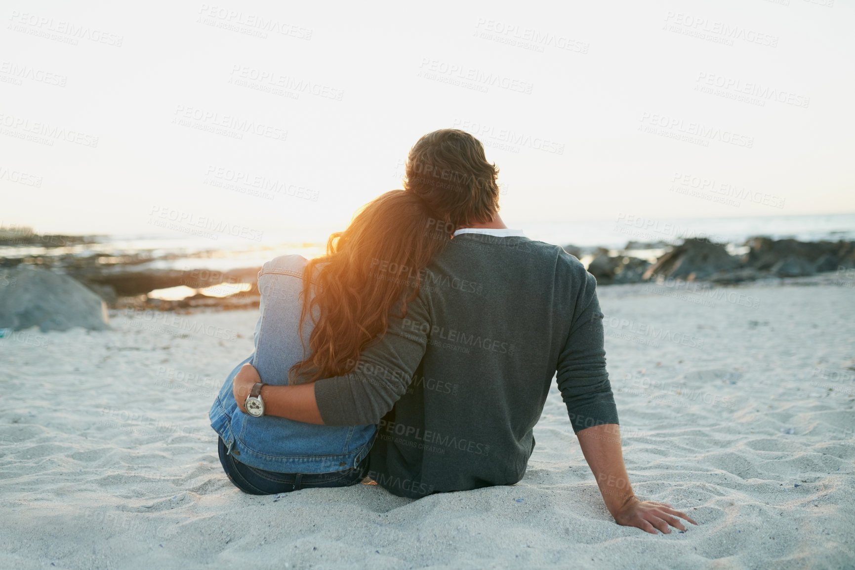 Buy stock photo Rearview shot of an affectionate young couple bonding at the beach