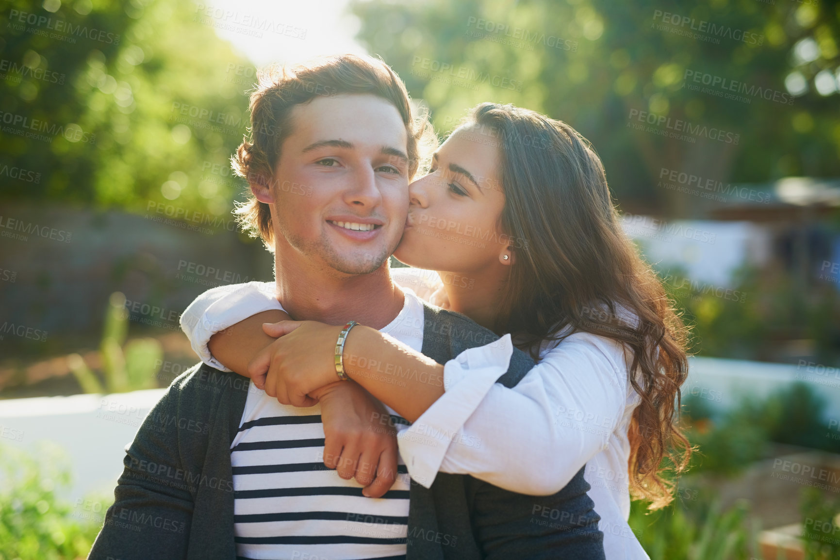 Buy stock photo Couple, home and kiss on cheek in garden on break with fun, affection and bonding for love in Spain. People, relationship and outside with smile for nature at backyard for support, care and trust