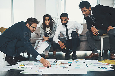 Buy stock photo Shot of businesspeople having a brainstorming session with documents spread out in front of them
