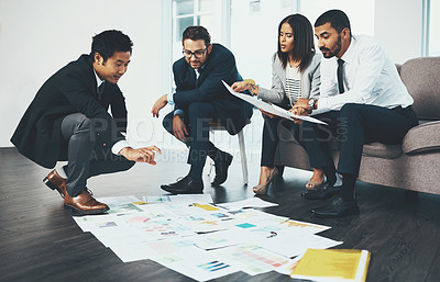 Buy stock photo Shot of businesspeople having a brainstorming session with documents spread out in front of them