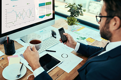 Buy stock photo Shot of a young businessman drinking a cup of tea while working in an office