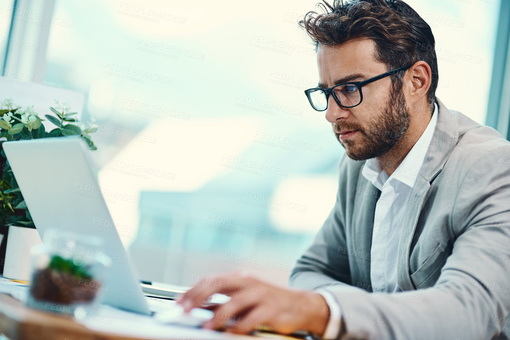 Buy stock photo Shot of a young businessman working on a laptop in an office