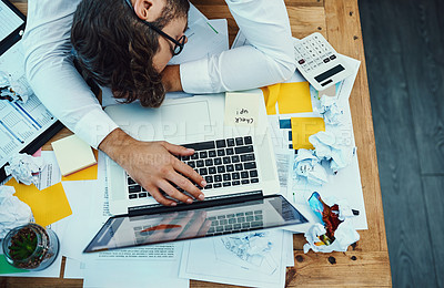 Buy stock photo High angle shot of a young businessman with his head down on an office desk