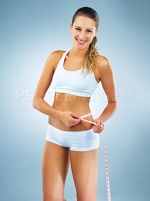 Buy stock photo Happy woman, portrait and size with measuring tape for lose weight, diet or strength in studio on a blue background. Young female person or attractive model with smile for slim body, waist or goals