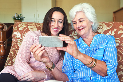 Buy stock photo Cropped shot of a senior woman and her granddaughter taking a selfie at home