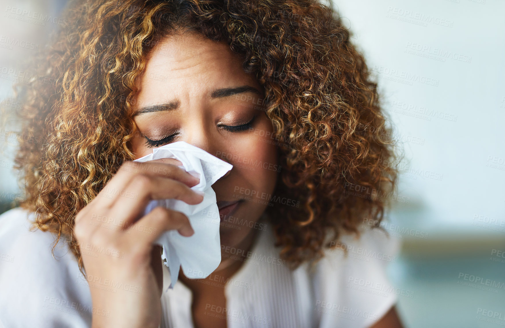 Buy stock photo Shot of a frustrated businesswoman using a tissue to wipe her nose while being seated in the office