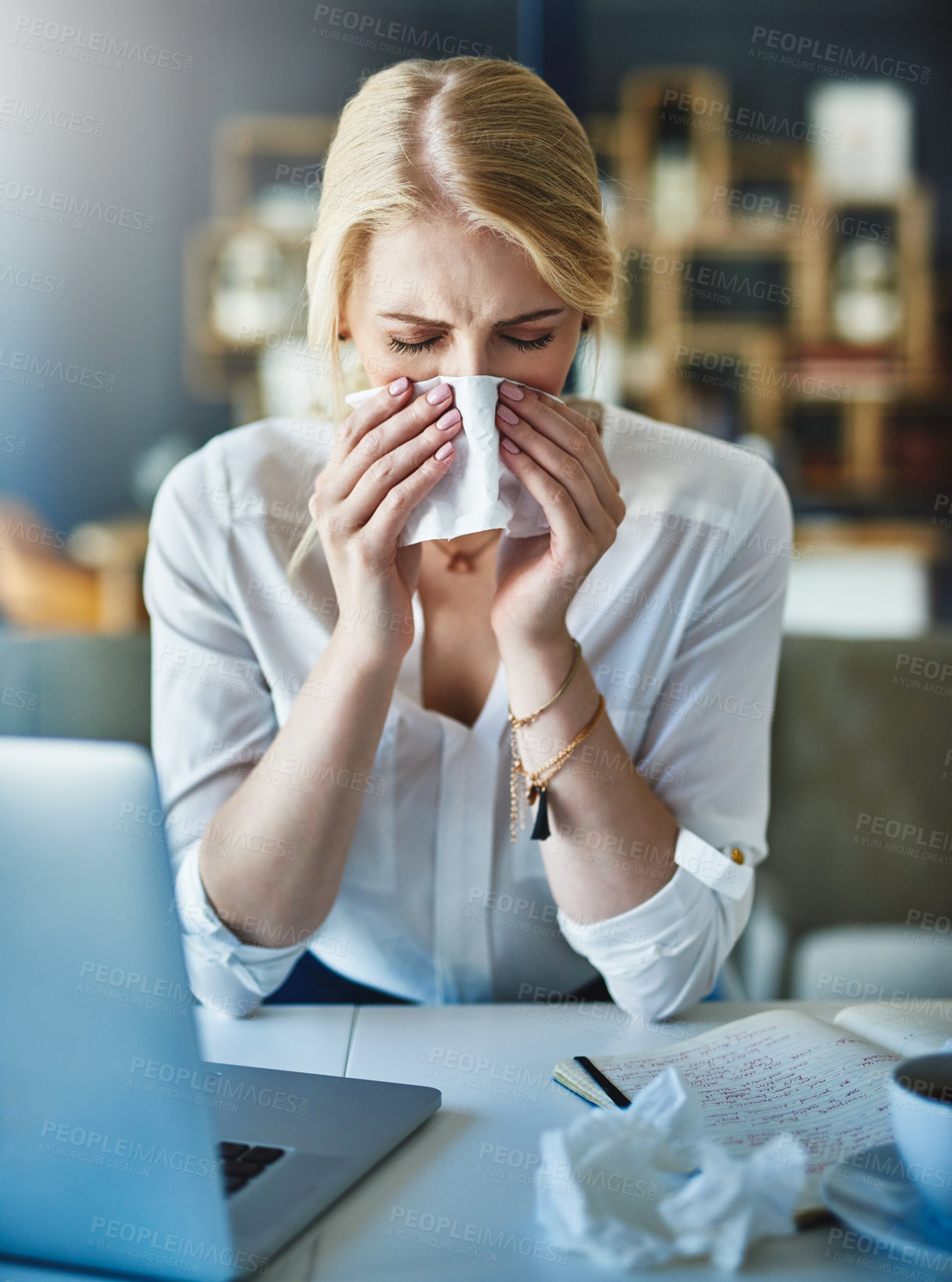 Buy stock photo Shot of a frustrated businesswoman using a tissue to sneeze in while being seated in the office