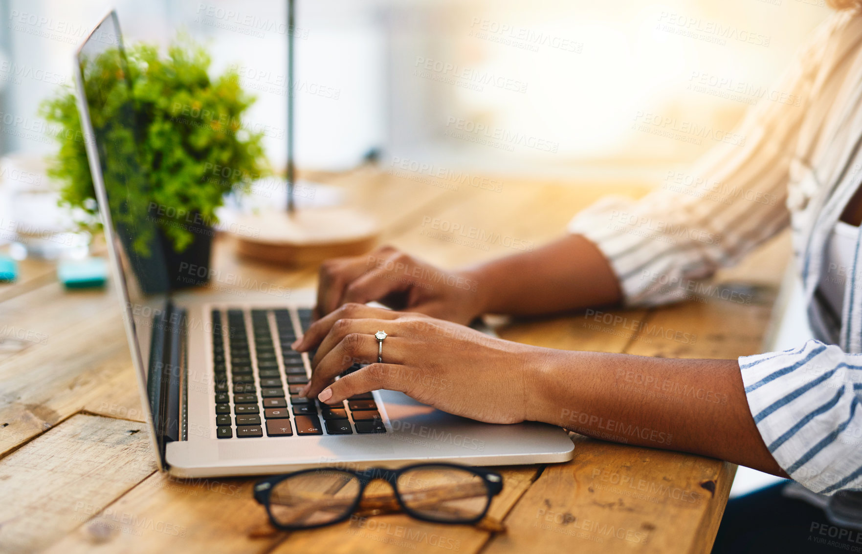 Buy stock photo Cropped shot of a woman using her laptop on a wooden table