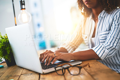 Buy stock photo Hands of a woman working with her laptop on a wooden table indoors. Closeup of entrepreneur typing in an open plan home office. Female blog writer brainstorming new creative ideas.