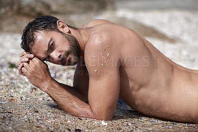 Buy stock photo Shot of a handsome young man lying outside on the beach