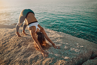 Buy stock photo Shot of woman doing the downward-facing dog pose on the beach