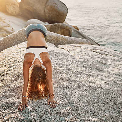 Buy stock photo Shot of woman doing the downward-facing dog pose on the beach
