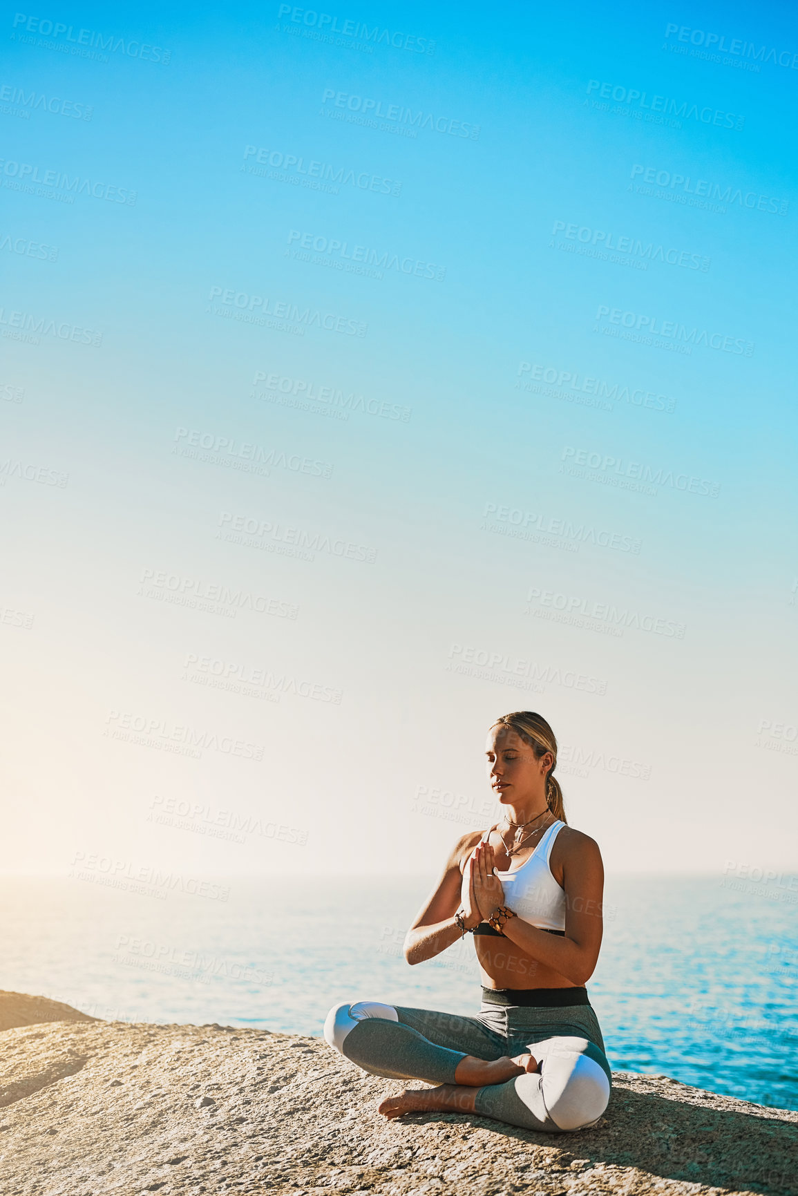 Buy stock photo Shot of an athletic young woman practicing yoga on the beach