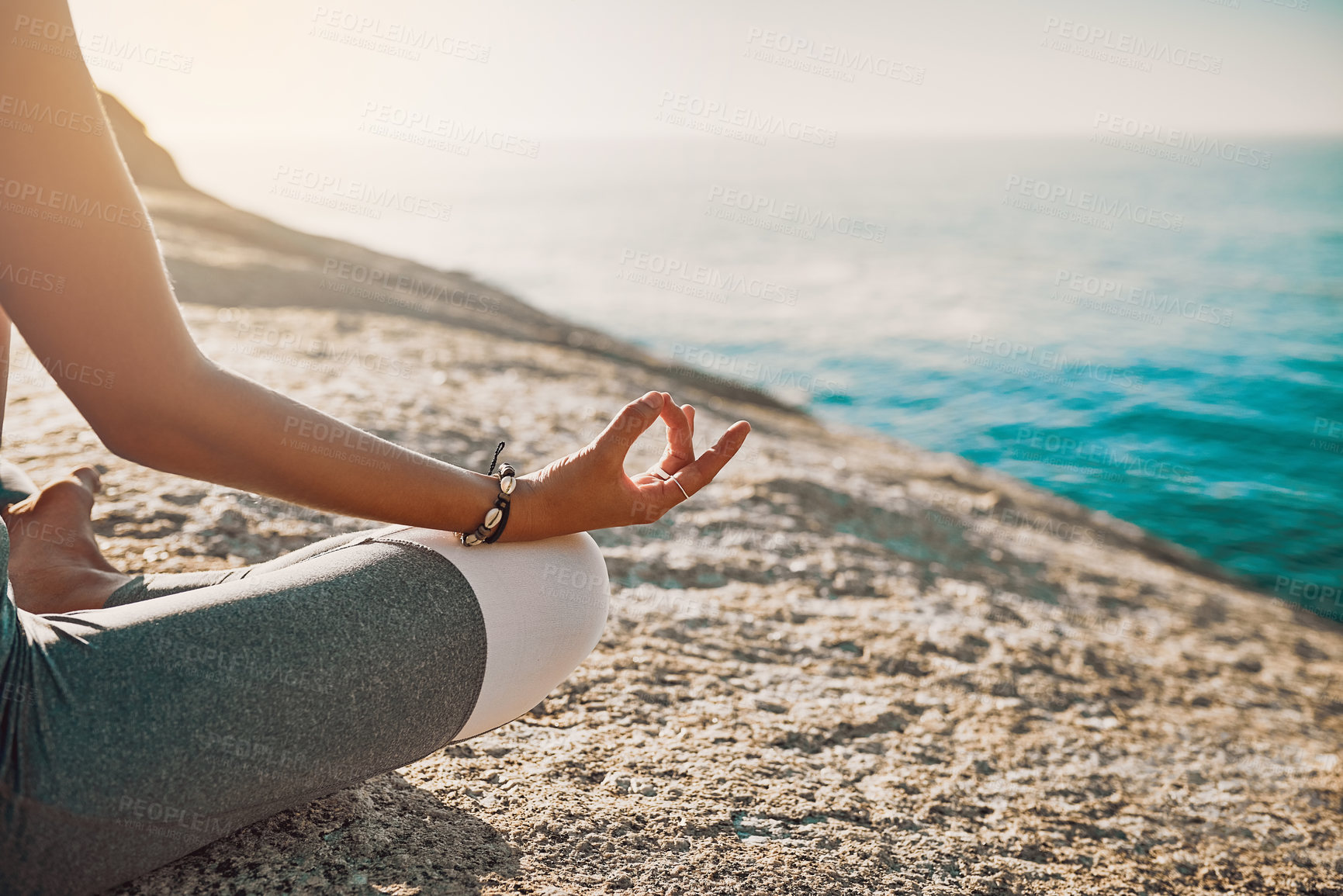 Buy stock photo Cropped shot of a woman practising the lotus pose on the beach