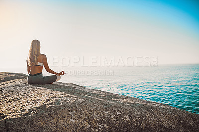 Buy stock photo Rearview shot of a young woman practicing yoga on the beach