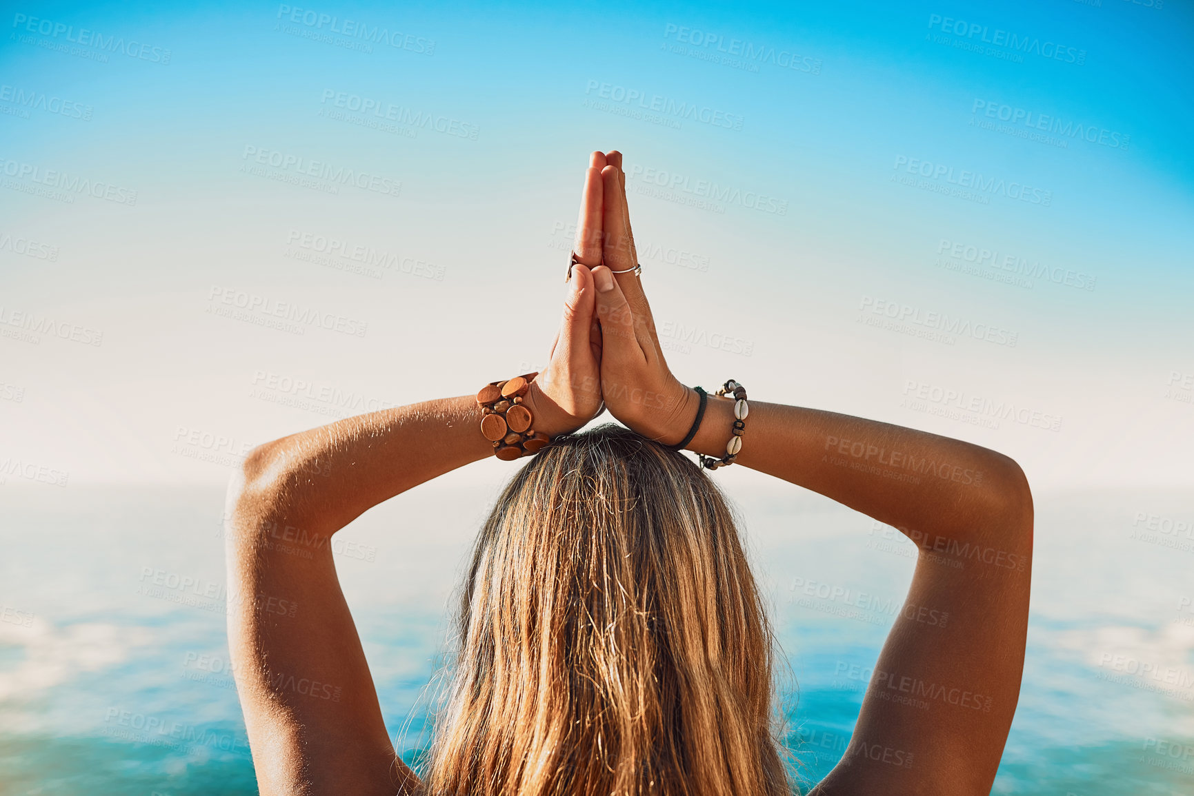 Buy stock photo Rearview shot of a young woman practicing yoga on the beach