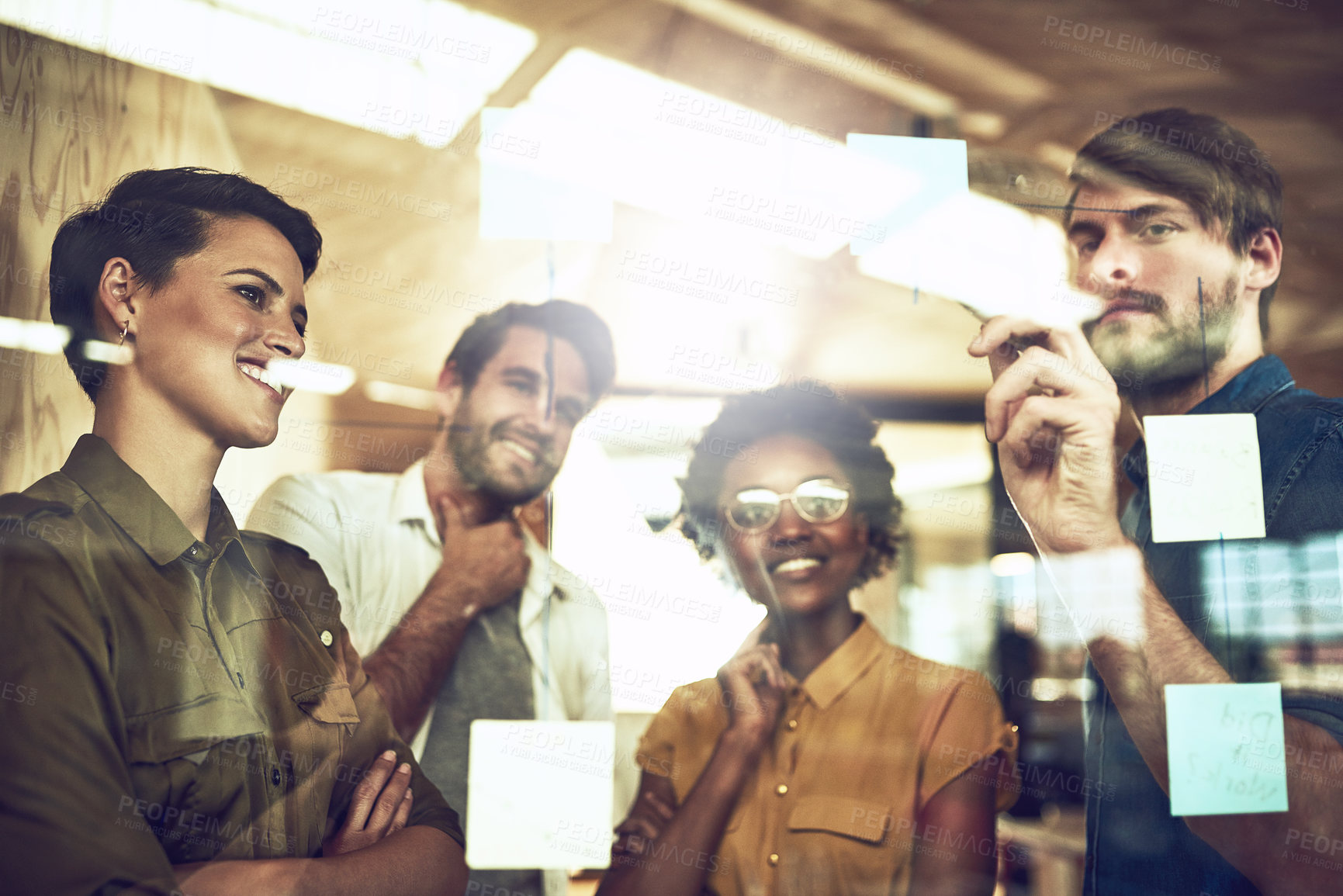 Buy stock photo Shot of a group of businesspeople brainstorming with notes on a glass wall