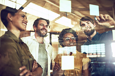 Buy stock photo Shot of a group of businesspeople brainstorming with notes on a glass wall