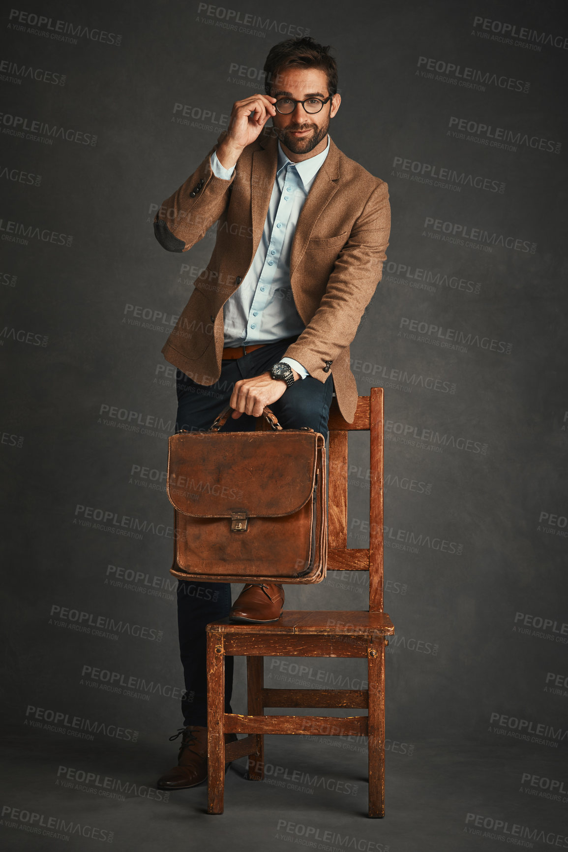 Buy stock photo Man, portrait and studio with chair for fashion, work bag and smart casual style for professional confidence. Male professor, gray background and glasses with jacket or cool, trendy blazer in Chicago