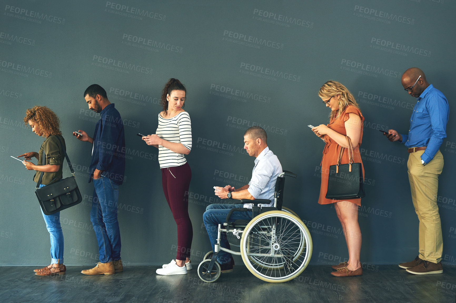 Buy stock photo Shot of a group of people standing in a row behind each other while using their phones