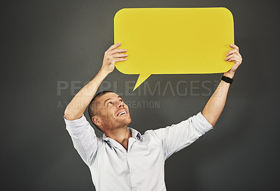 Buy stock photo Studio shot of a man holding a speech bubble against a gray background