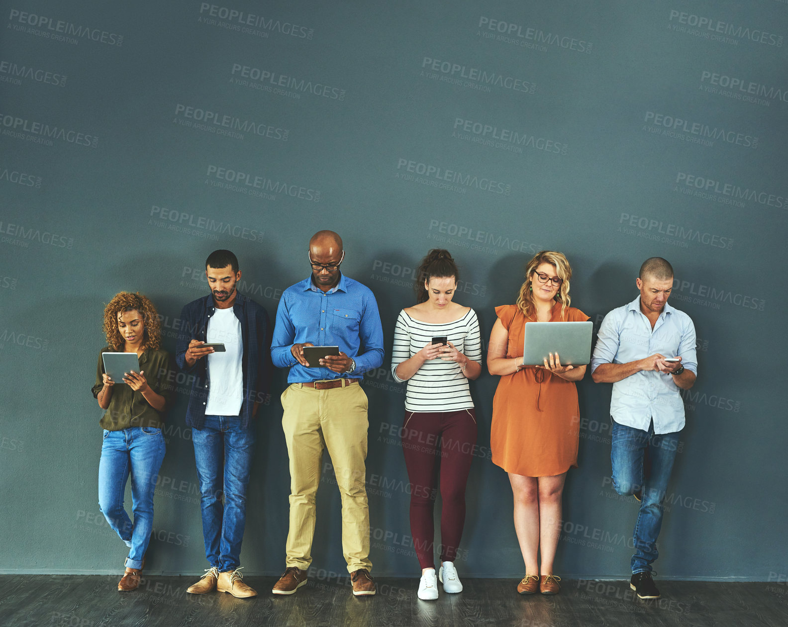 Buy stock photo Diverse group of people browsing social media on a phone, tablet and laptop in studio on a grey background. Networking, surfing the internet and posting online with wireless technology and copyspace