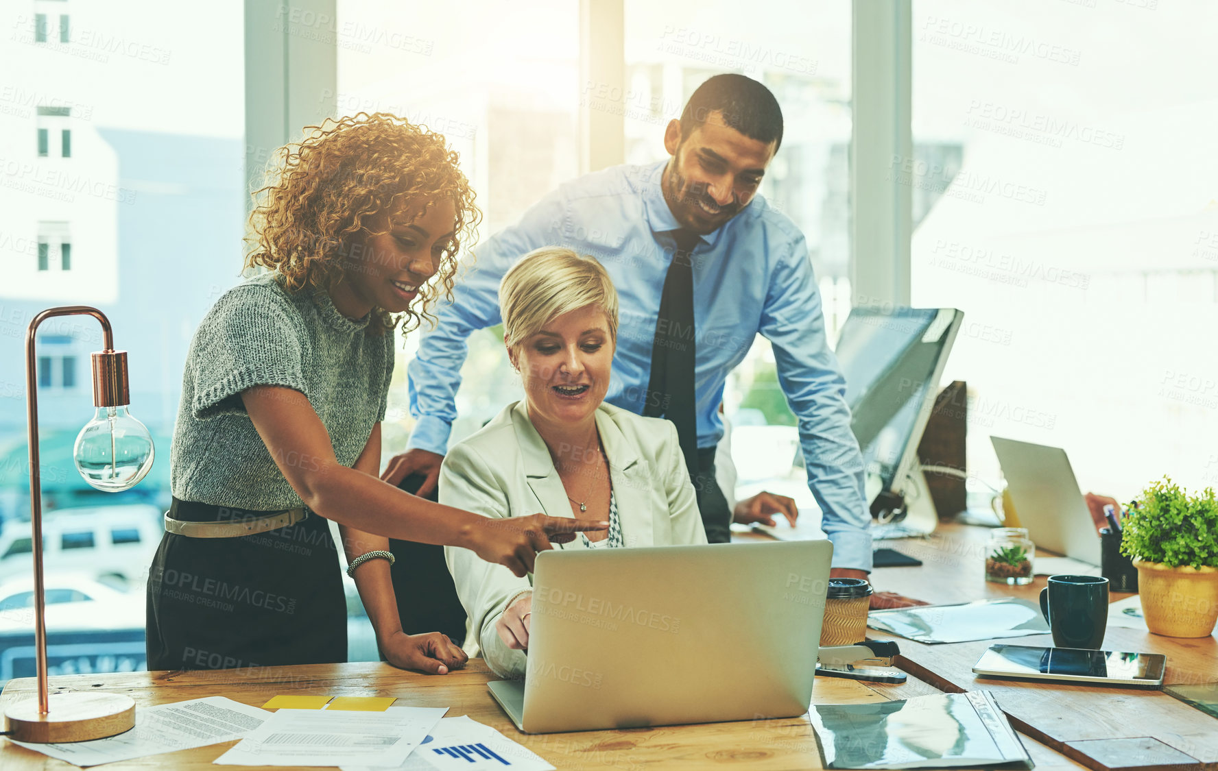 Buy stock photo Shot of a group of businesspeople working together on a laptop in an office