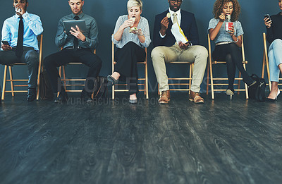 Buy stock photo Shot of a group of well-dressed business people seated in line while waiting to be interview