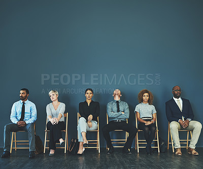 Buy stock photo Shot of a group of well-dressed business people seated in line while waiting to be interview