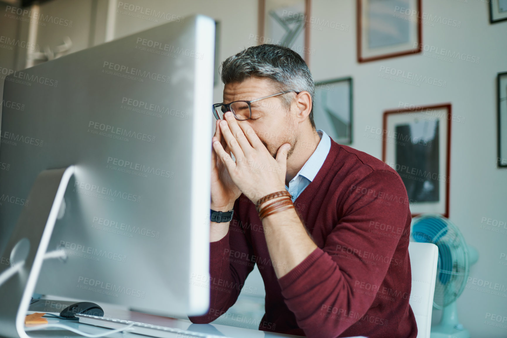 Buy stock photo Shot of a mature businessman looking stressed out while working on a computer in an office