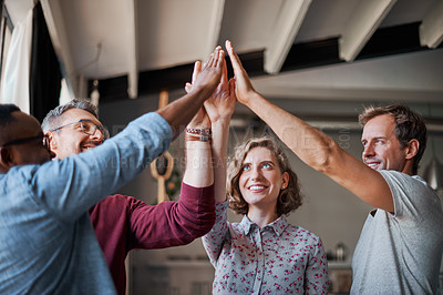 Buy stock photo Shot of a group of businesspeople high fiving in an office