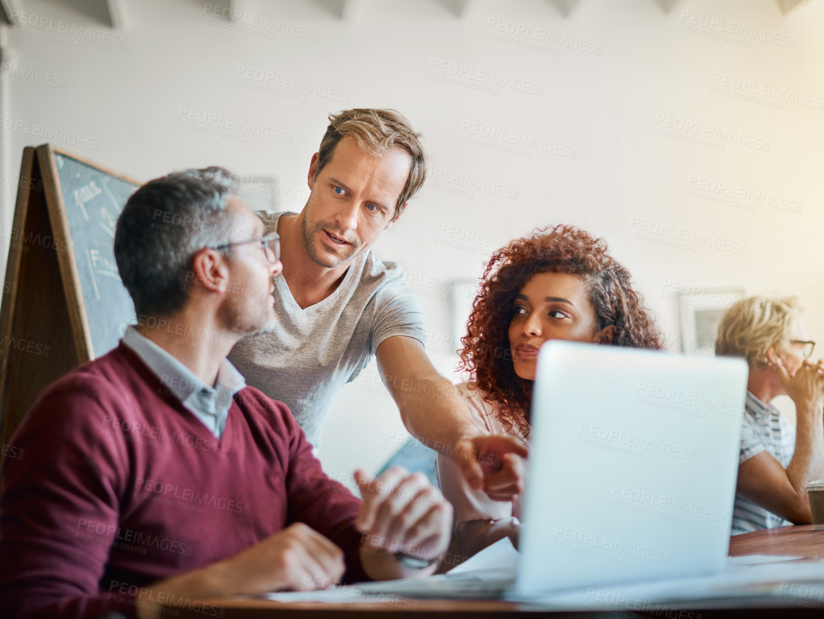 Buy stock photo Shot of a group of businesspeople working together on a laptop in an office