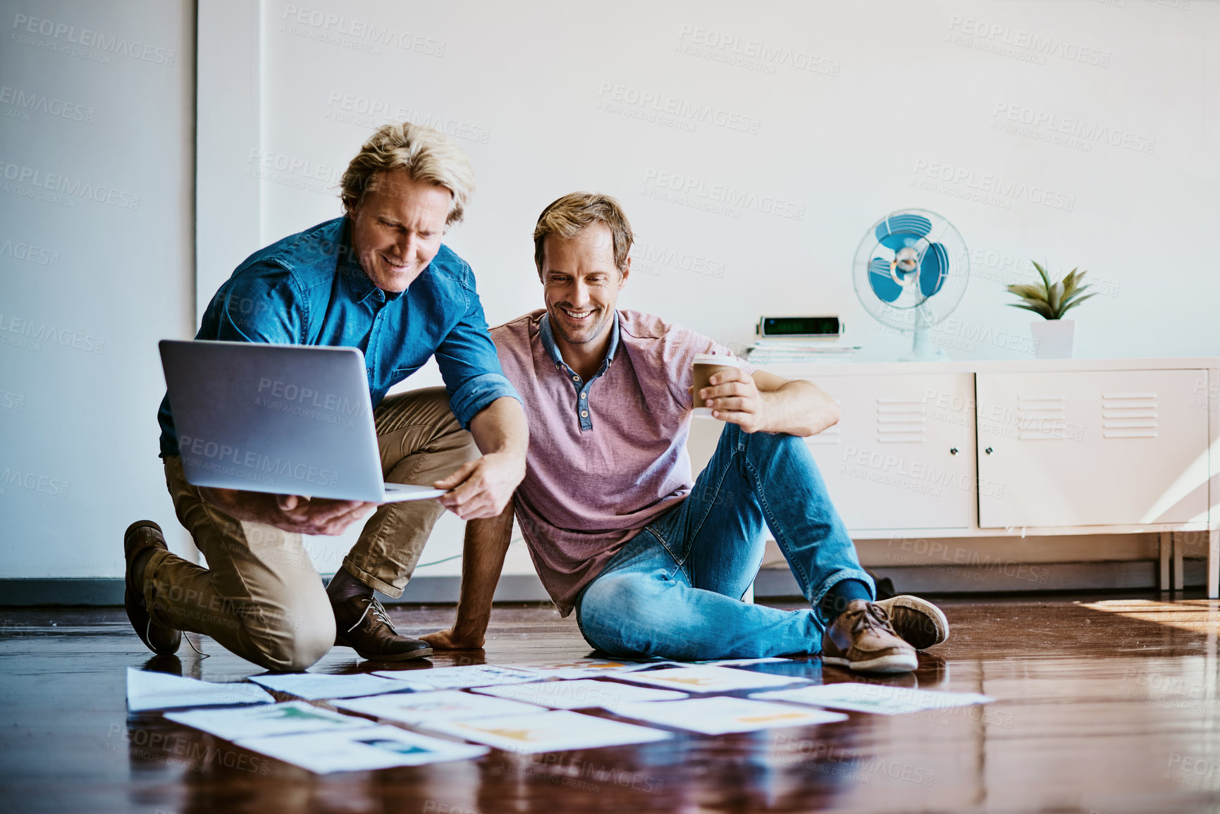 Buy stock photo Shot of two designers brainstorming together on the floor in an office