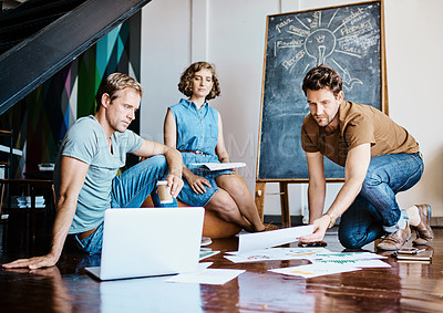Buy stock photo Shot of a group of designers brainstorming together on the floor in an office