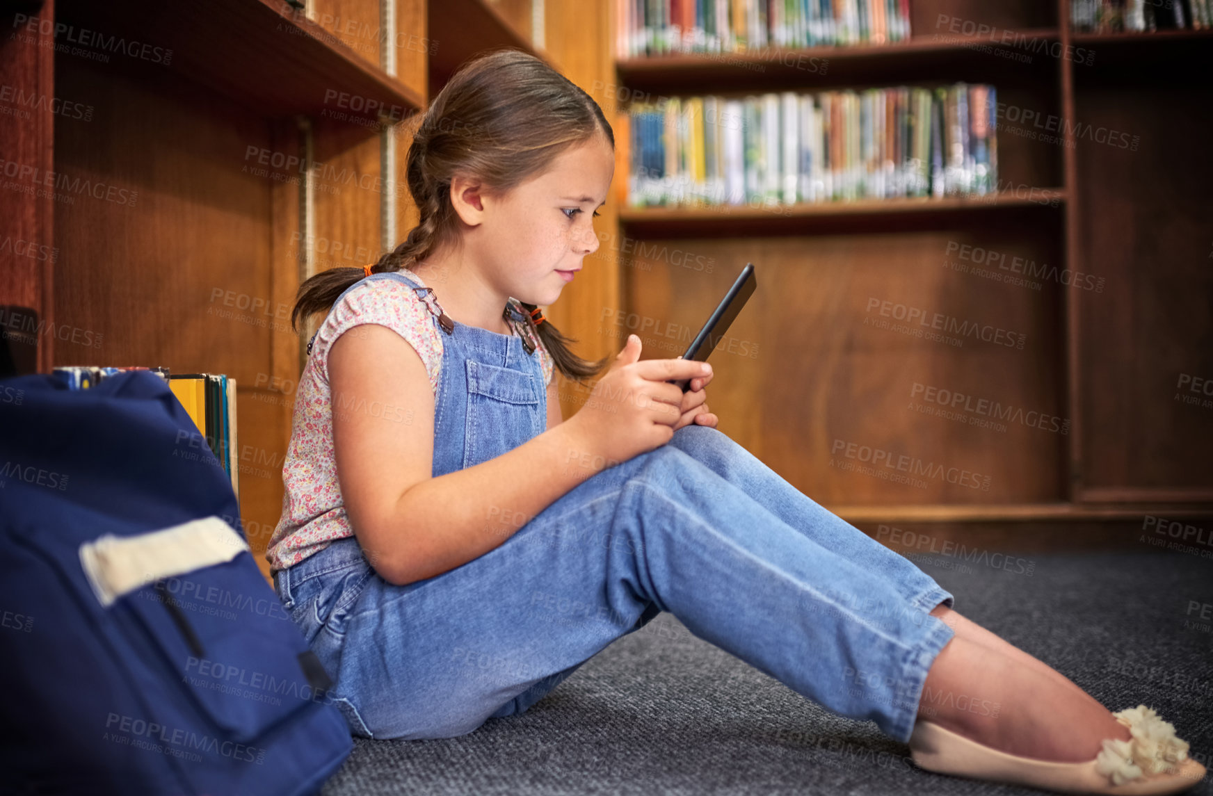 Buy stock photo Shot of a young girl using a digital tablet at school