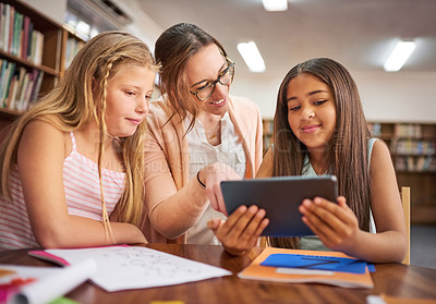 Buy stock photo Shot of a teacher helping her students use a digital tablet at school