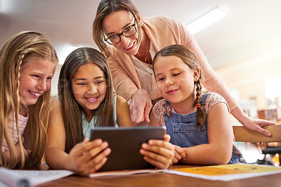 Buy stock photo Shot of a teacher helping her students use a digital tablet at school