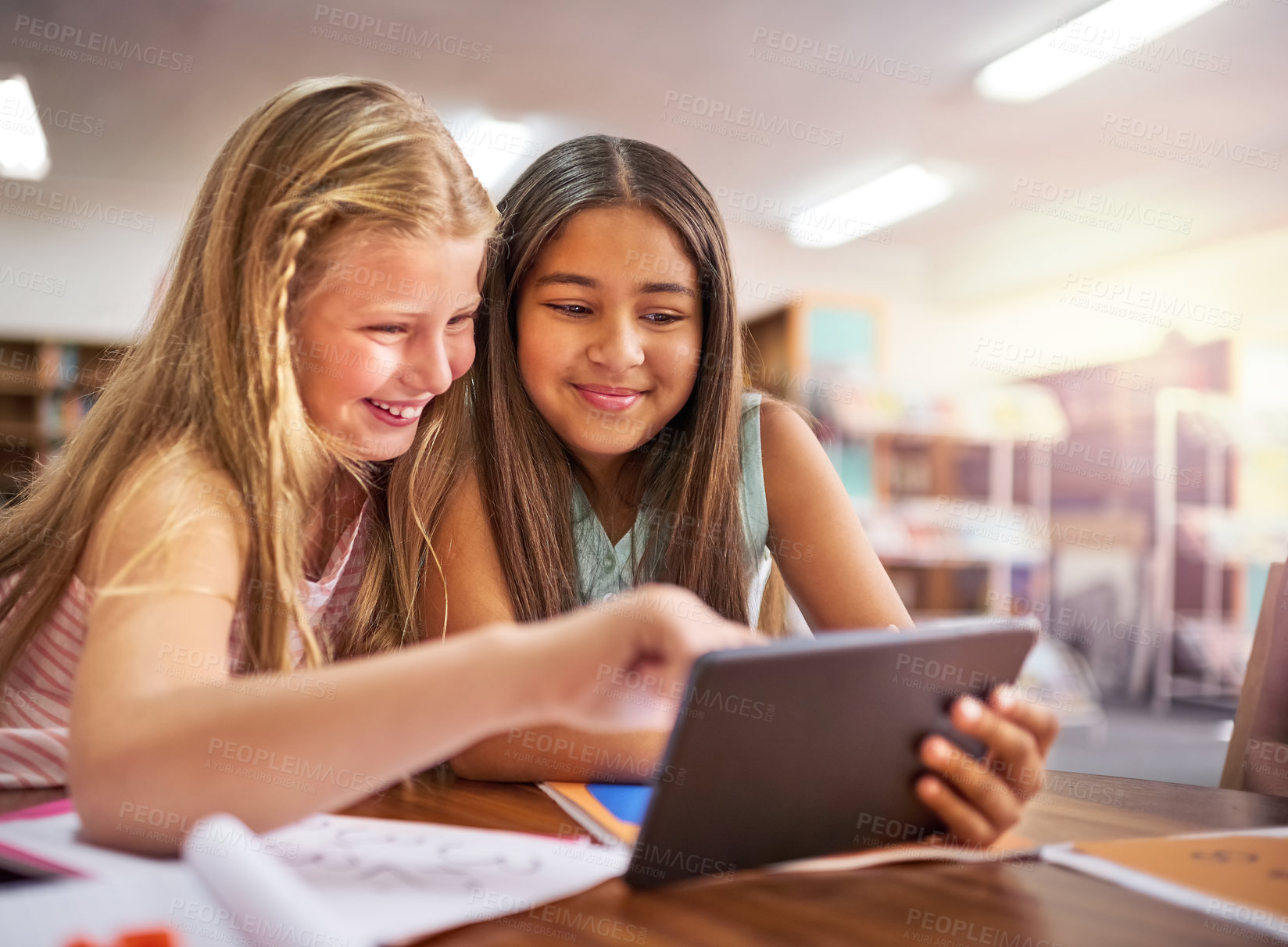 Buy stock photo Shot of two young girls using a digital tablet at school