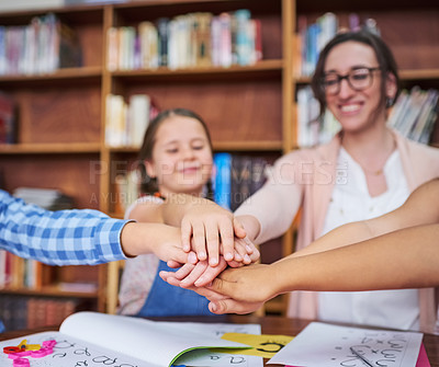 Buy stock photo Shot of a teacher and her students joining their hands together in unity at school
