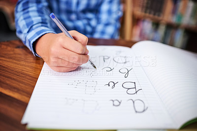 Buy stock photo Shot of an unrecognisable young boy writing in a book at school
