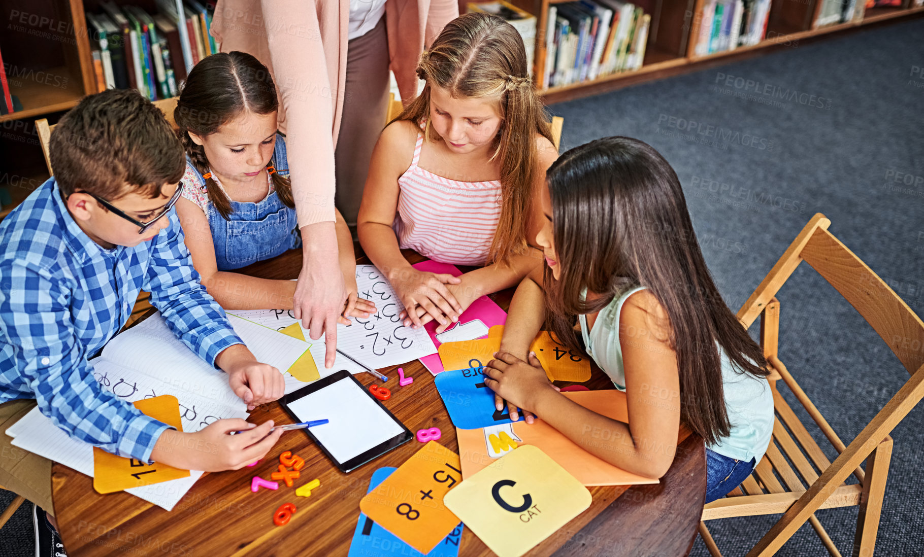 Buy stock photo Children, teacher and tablet for education with group, mockup space and blank screen in classroom. People, above and learning with books, maths and point at touchscreen for development at school