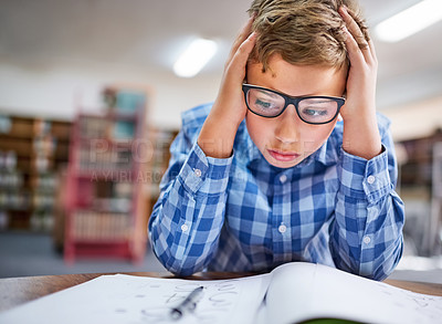 Buy stock photo Shot of a young boy looking stressed out while working in class at school