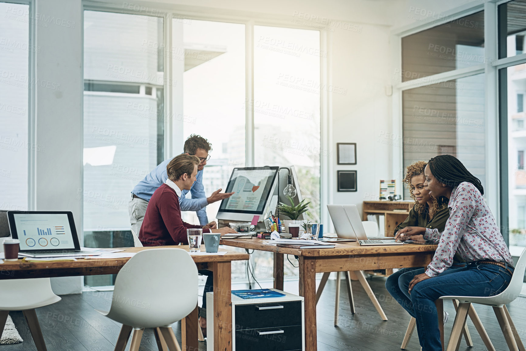 Buy stock photo Shot of a group of colleagues working together at their desks in a modern office