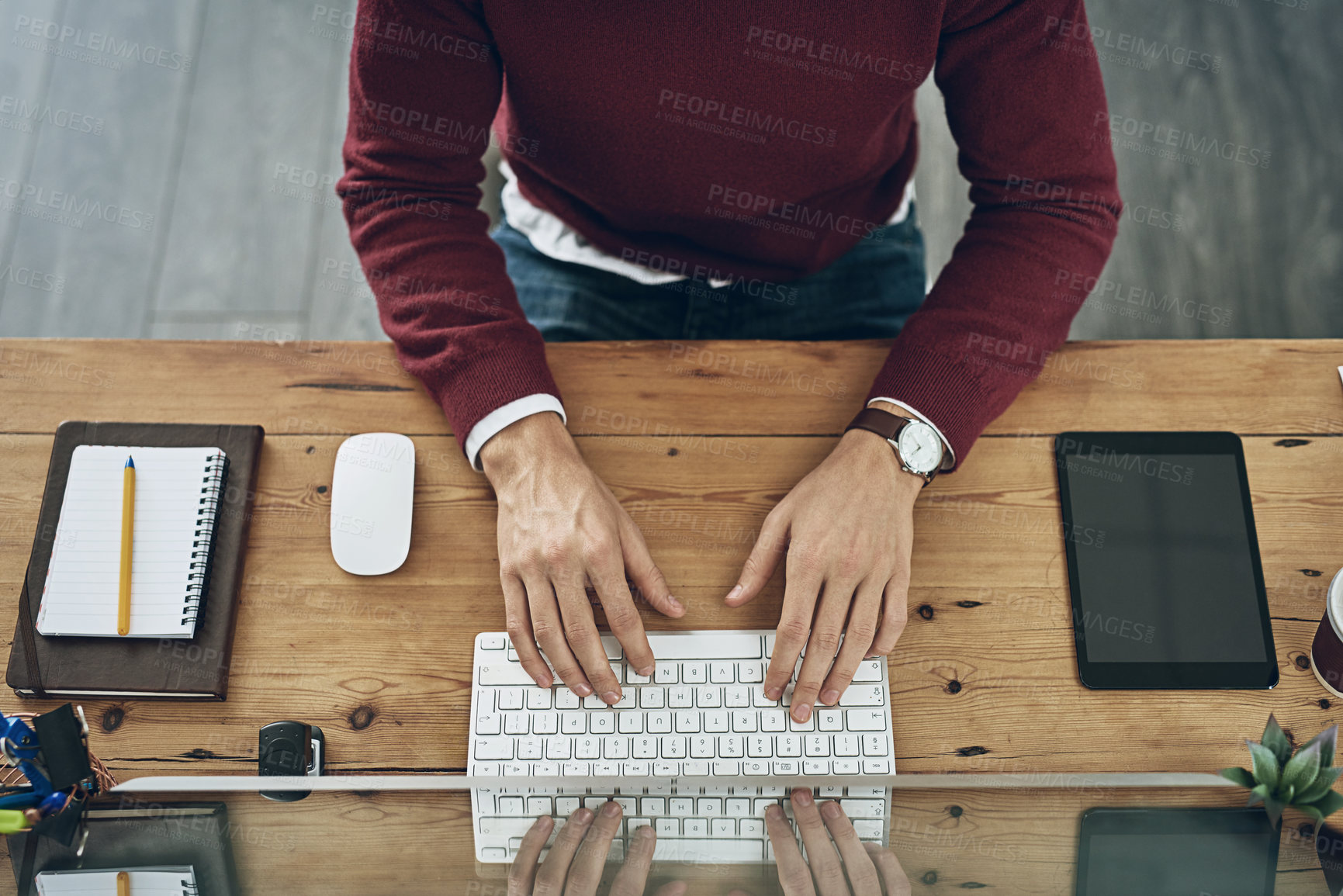 Buy stock photo High angle shot of a man using a computer at his desk in a modern office