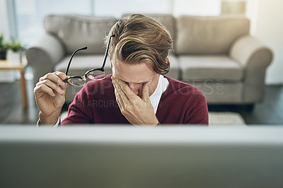 Buy stock photo Shot of a young man suffering from stress while using a computer at his work desk