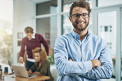 Buy stock photo Portrait of a confident young man with his colleagues in the background at work