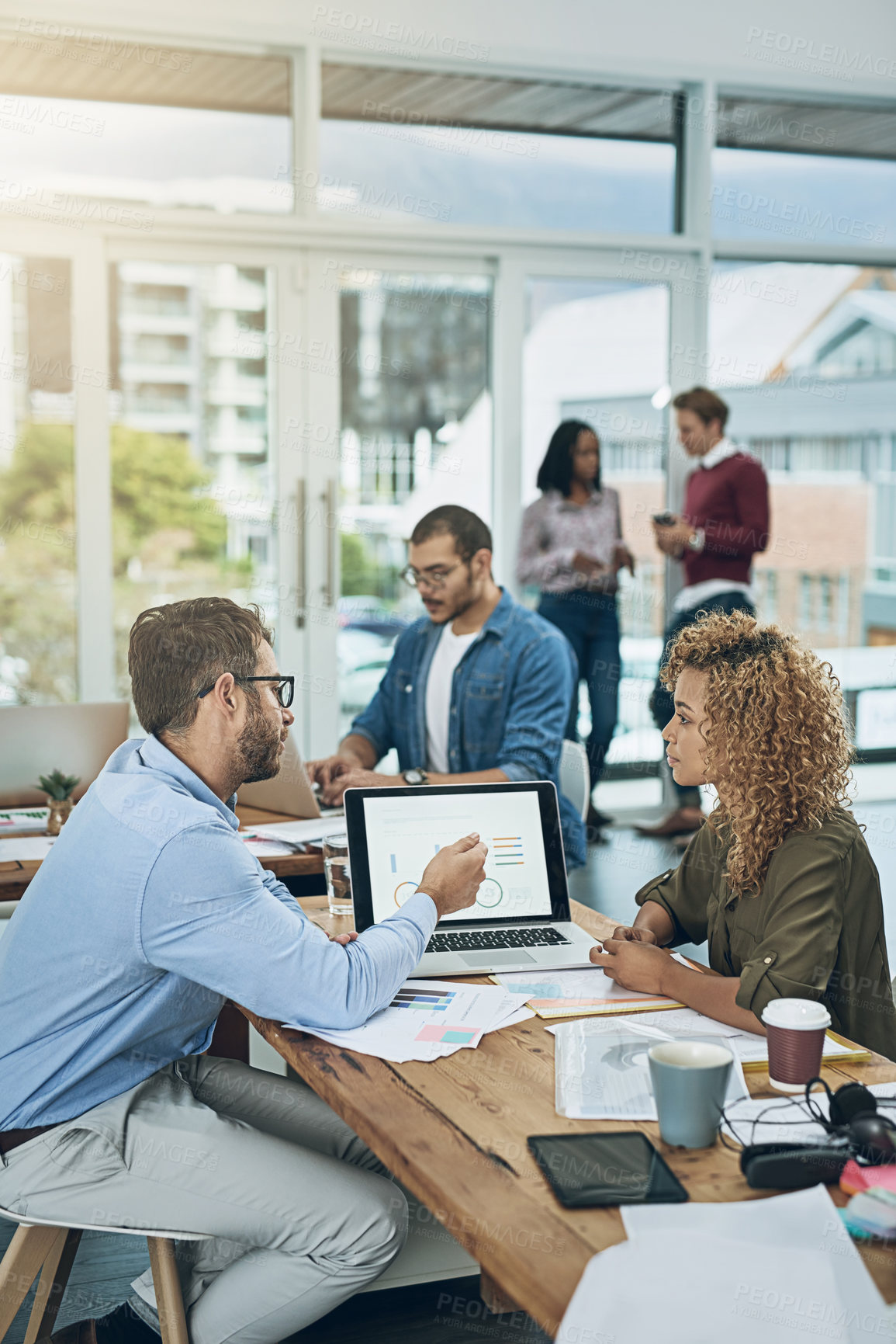 Buy stock photo Shot of two young colleagues using a laptop together in a modern office